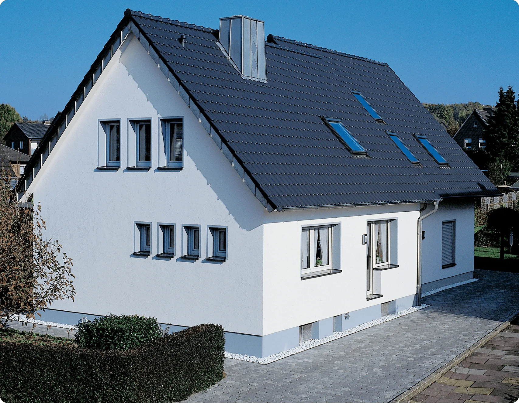 Nachher: Einfamilienhaus mit weiß verputzter Fassade und dunklem Dach