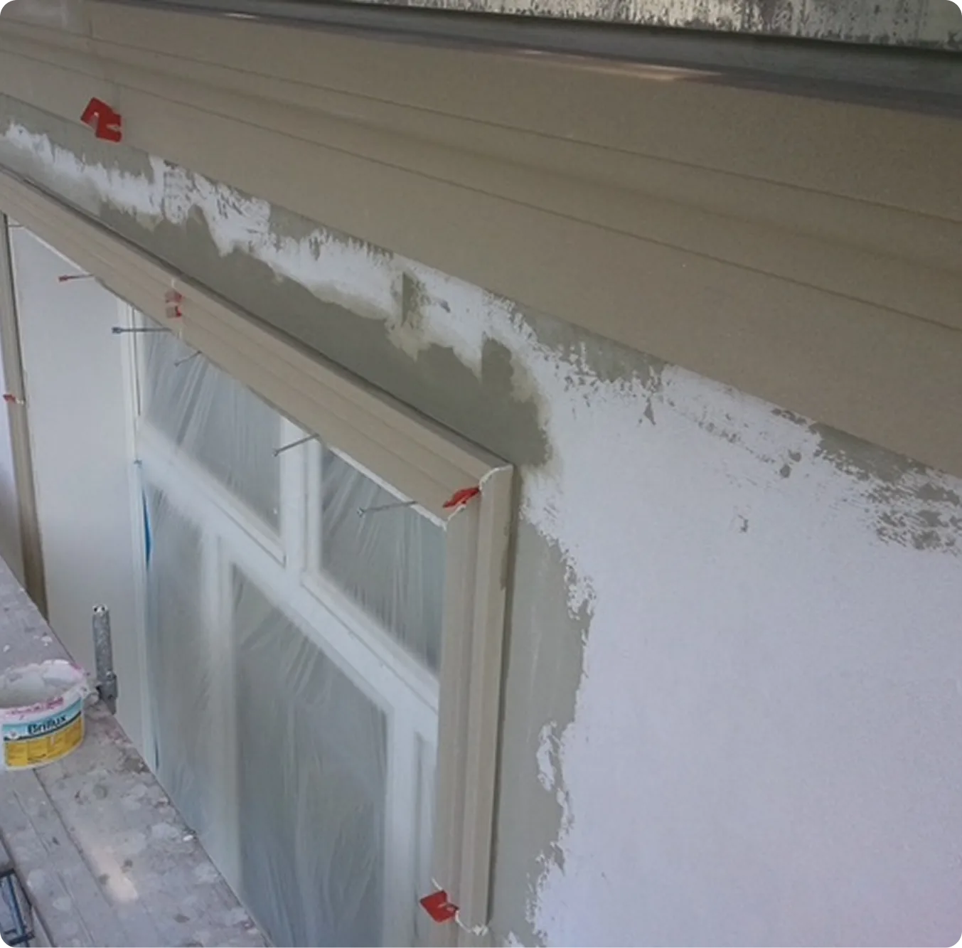 Neu verputzte Fensterlaibung an einer Fassade, Fenster abgeklebt