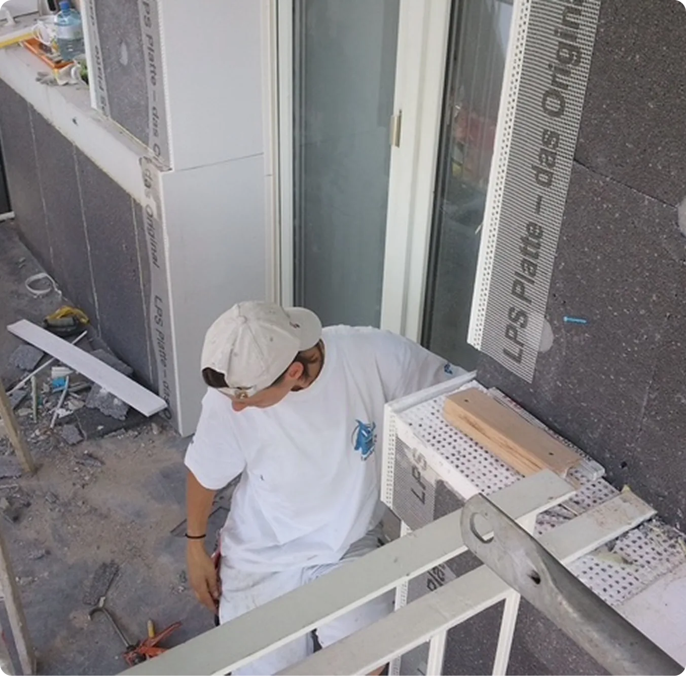 Handwerker bringt Dämmplatten und Kantenprofile am Balkon an
