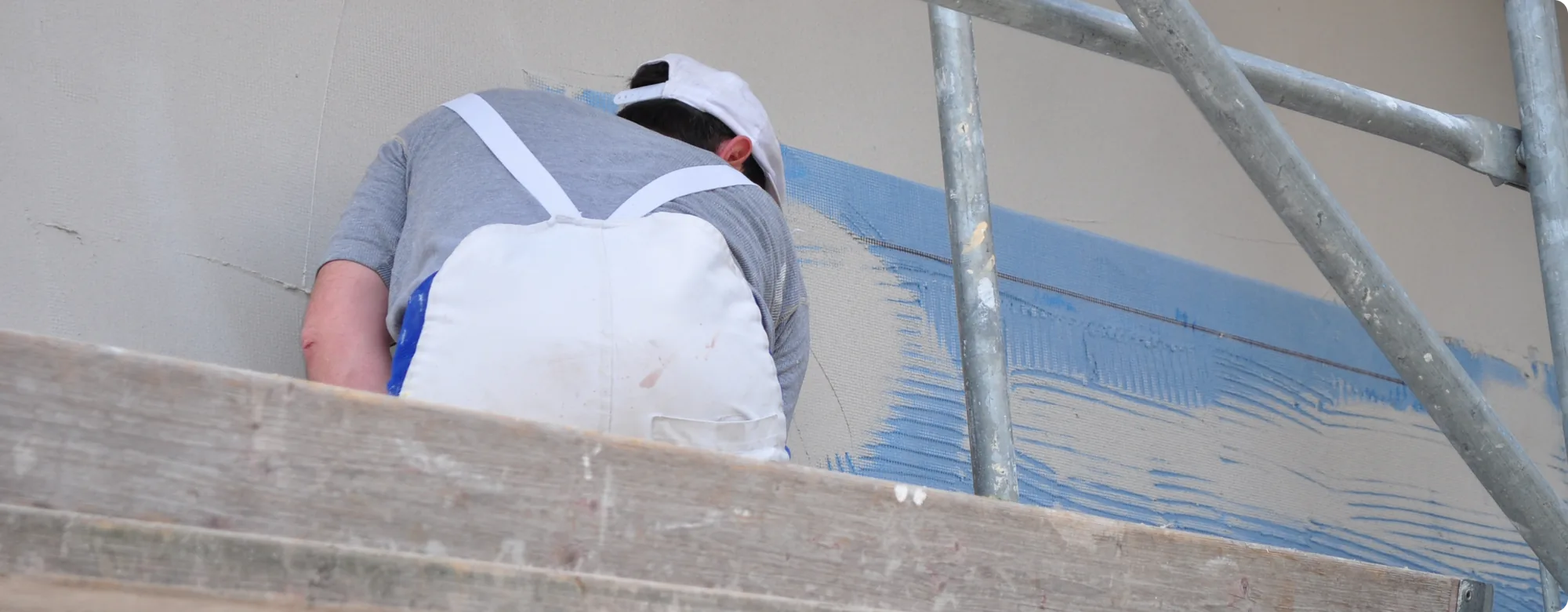 Maler auf dem Gerüst bei der Arbeit an einer Fassade