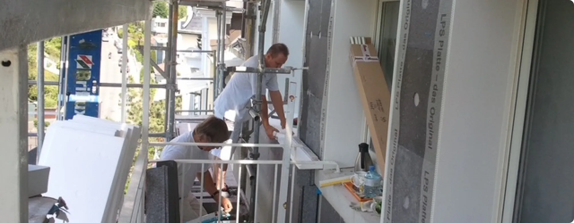 Zwei Handwerker bringen Dämmplatten für ein Wärmedämmverbundsystem an