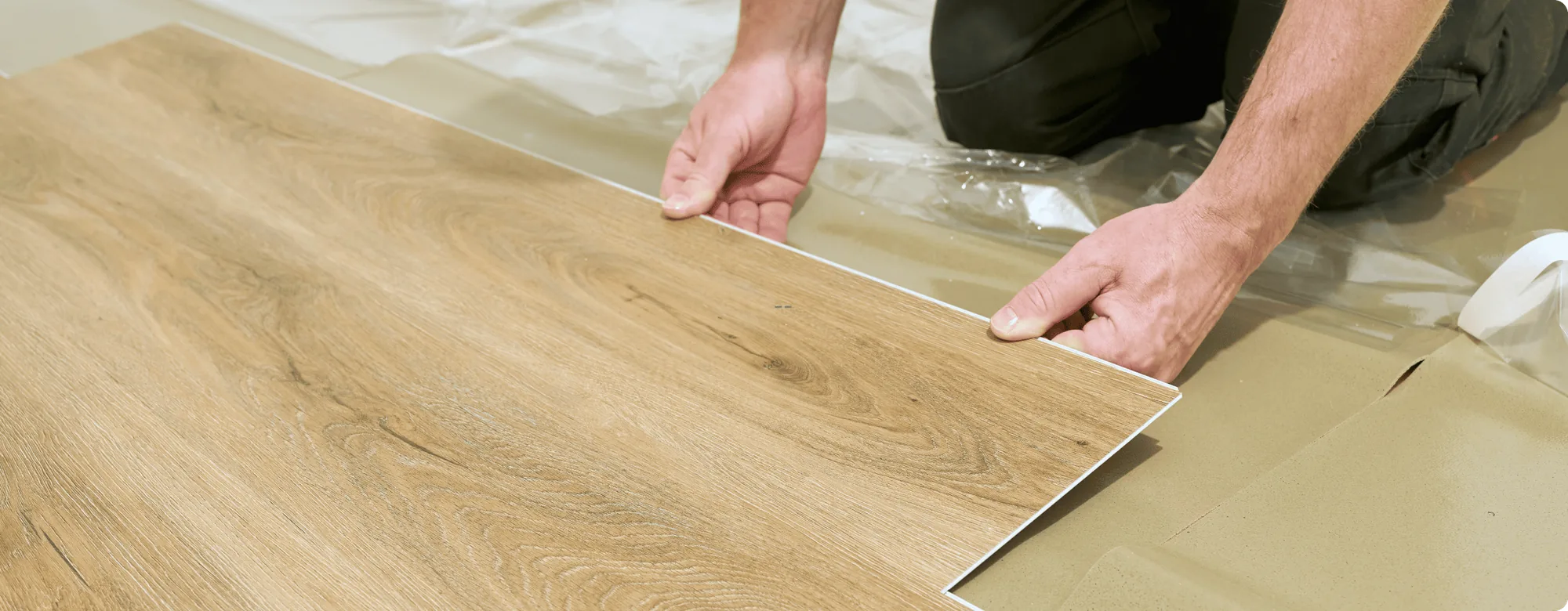 Handwerker verlegt Vinylboden in Holzoptik auf Trittschalldämmung