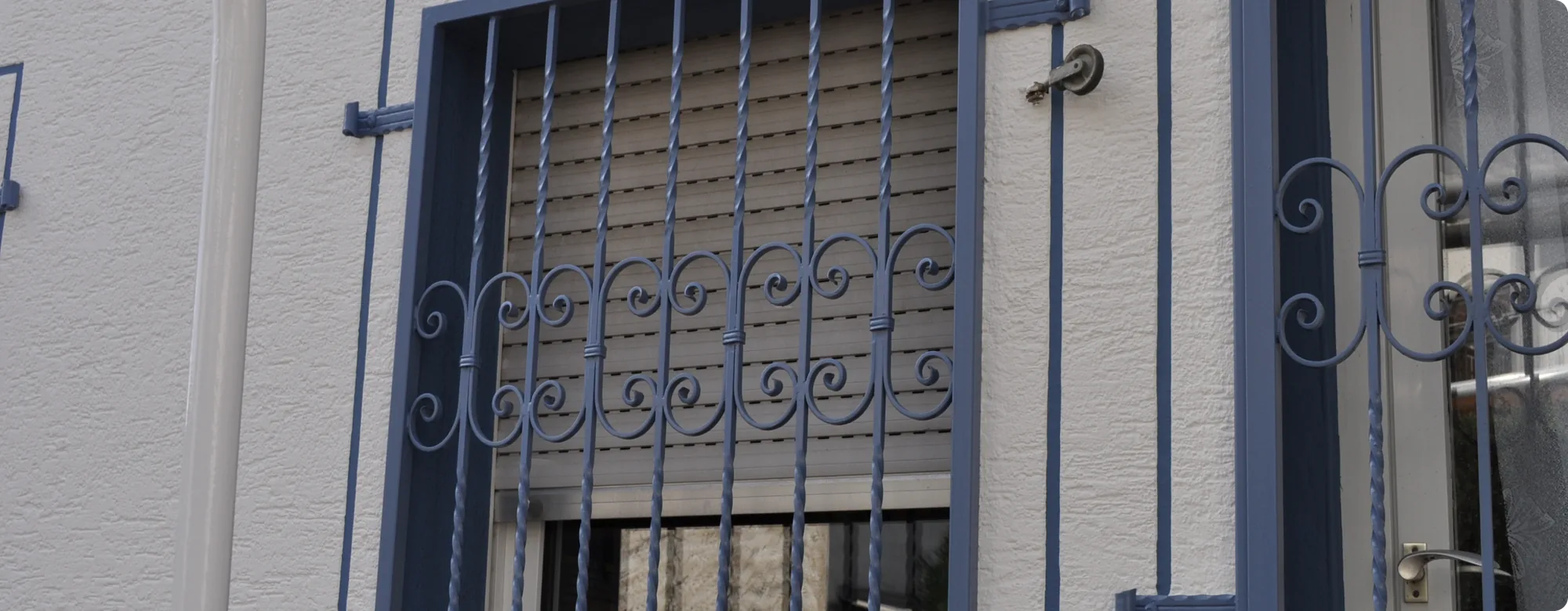 Lackiertes blaues Fenstergitter aus Metall an einer Hauswand