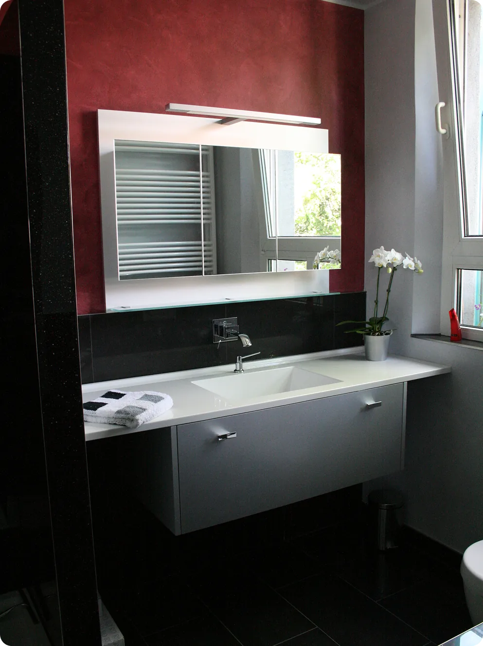 Badezimmer mit roter Wand in Spachteltechnik und Waschtisch