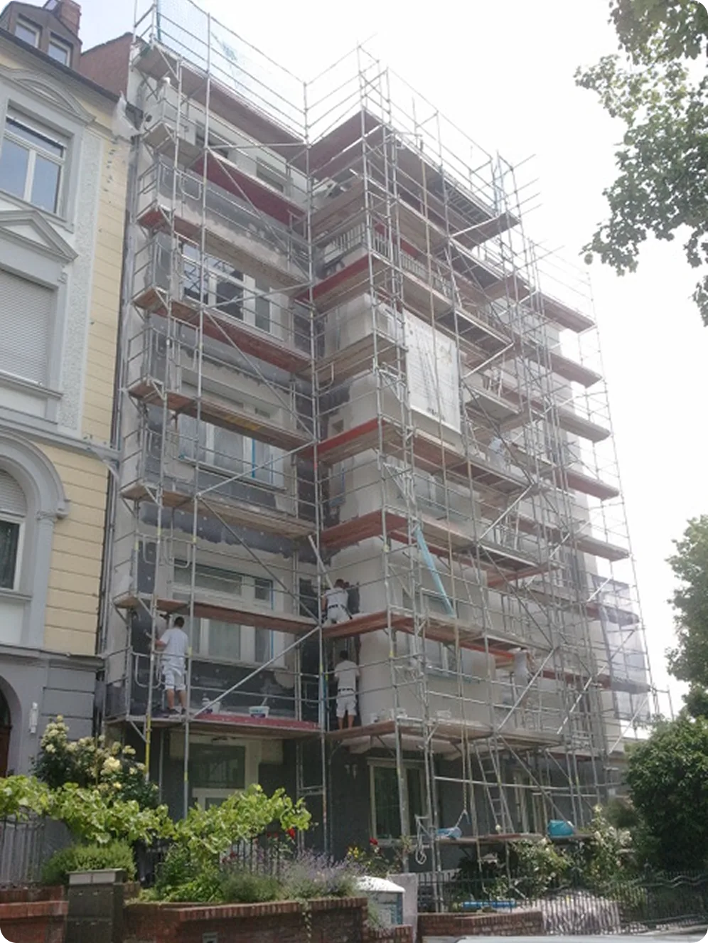 Eingerüstetes Mehrfamilienhaus, Maler arbeiten an der Fassade