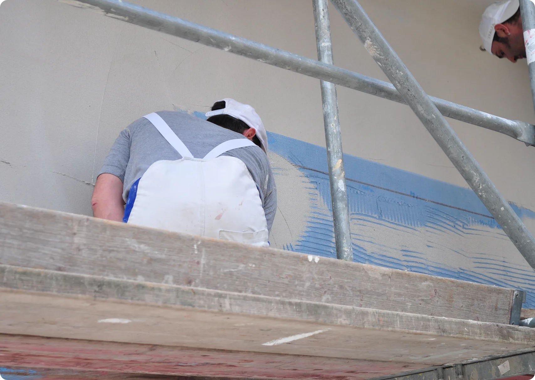 Stuckateur auf dem Gerüst verputzt eine Fassade