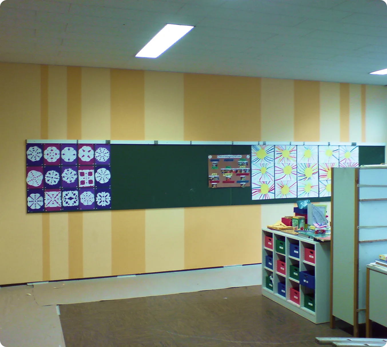 Klassenzimmer mit Wandgestaltung in gelben und orangen Streifen