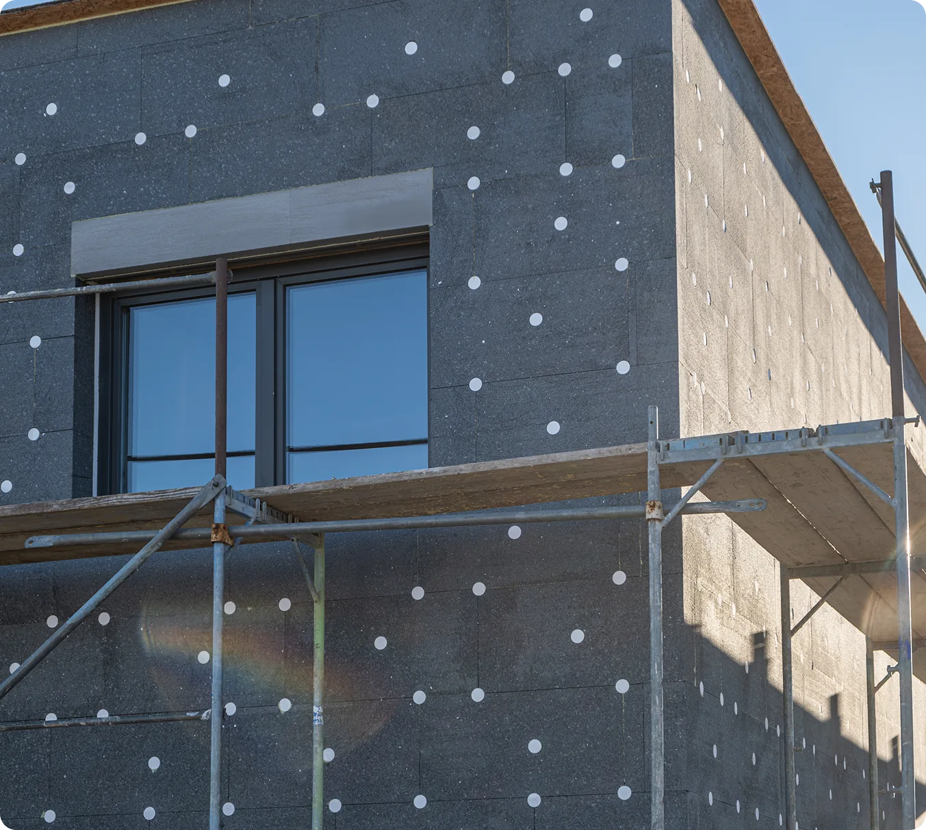Neubau mit gedübelten Dämmplatten am Fenster, davor ein Gerüst